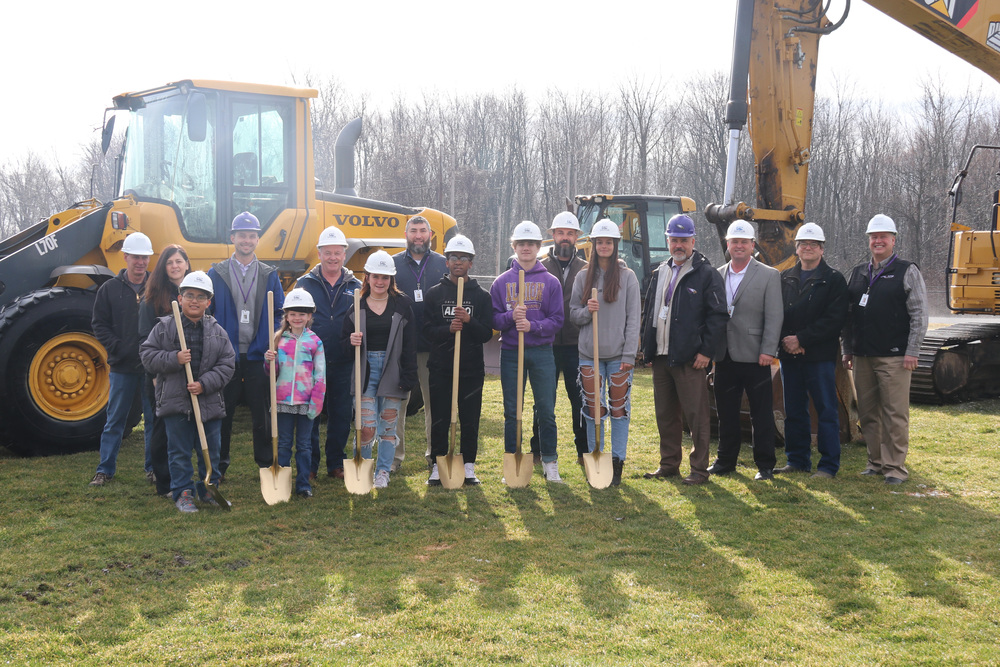 students and officials pose in front of machinery for groundbreaking