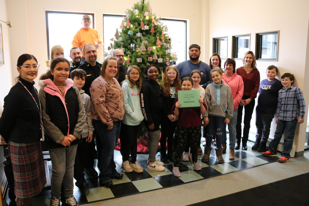 students and village officials stand in front of decorated tree