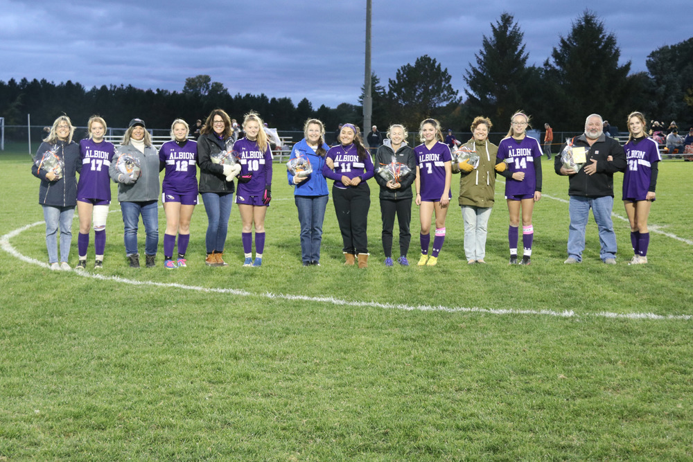 senior soccer players stand with their selected teachers