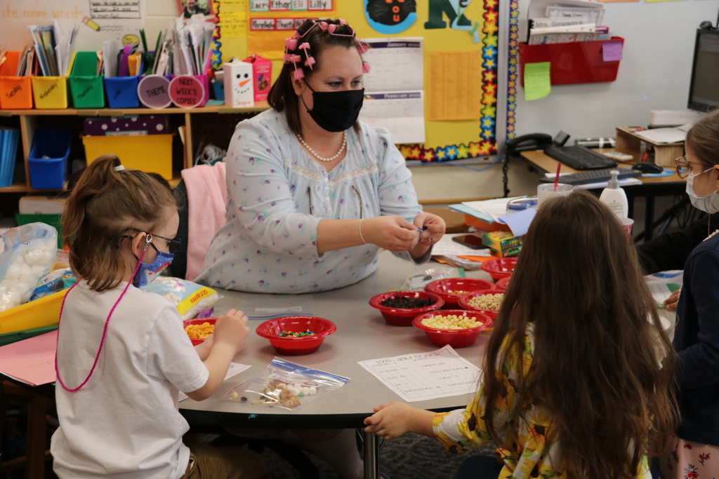a teacher dressed as a grandma hands out craft supplies to students