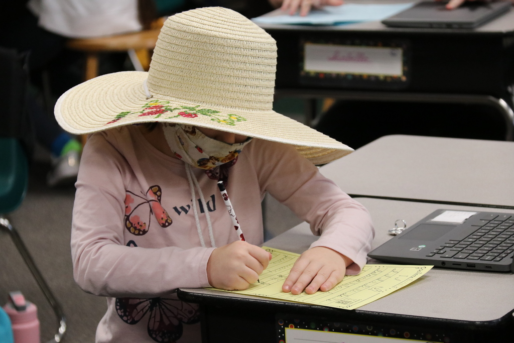 a student works on an assignment wearing a sun hat