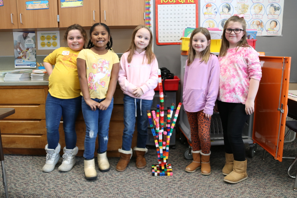 students stand next to their tower created with blocks