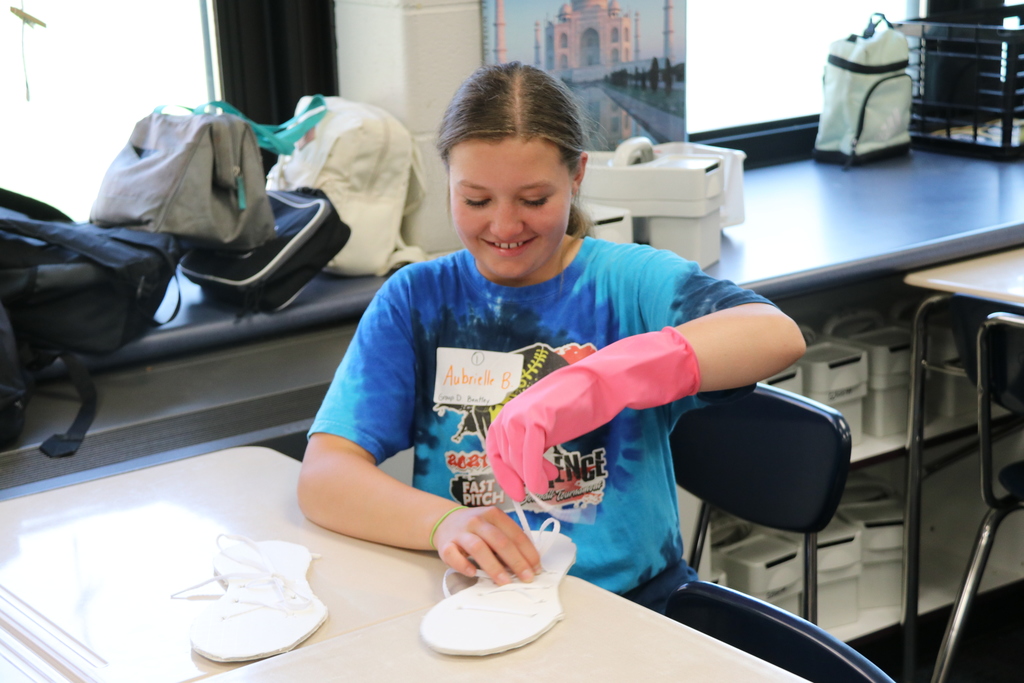 a student wears large gloves while attempting an activity