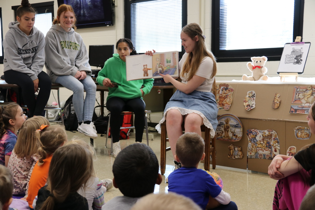 a high school student reads to the prek class