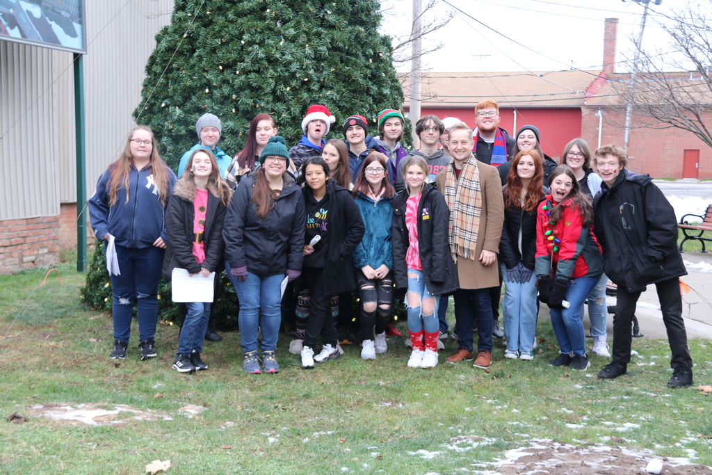 choir poses in front of downtown Christmas tree