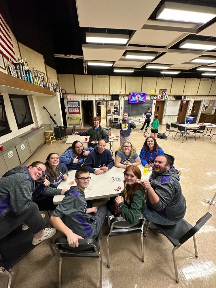 student and staff pause for a photo during a card game 
