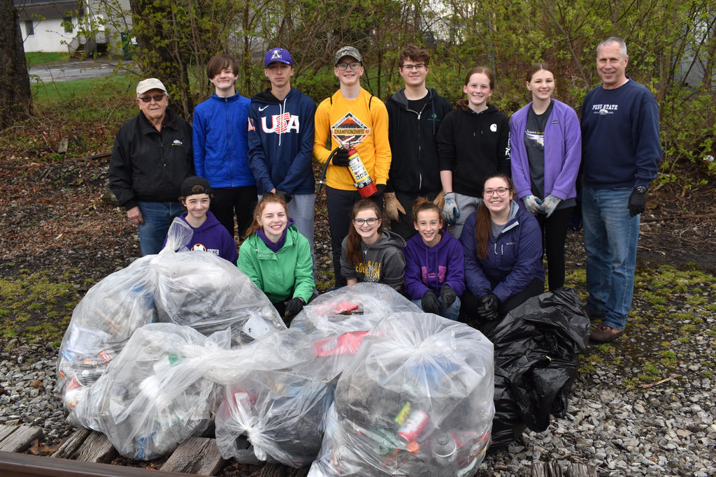 Interact students with advisor and Rotary members pose in front of collected trash