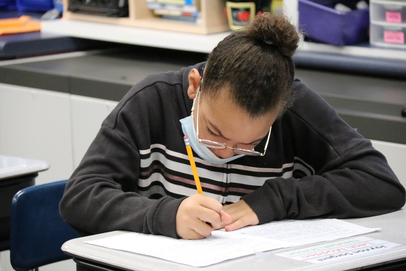 A student works on her pen pal letter