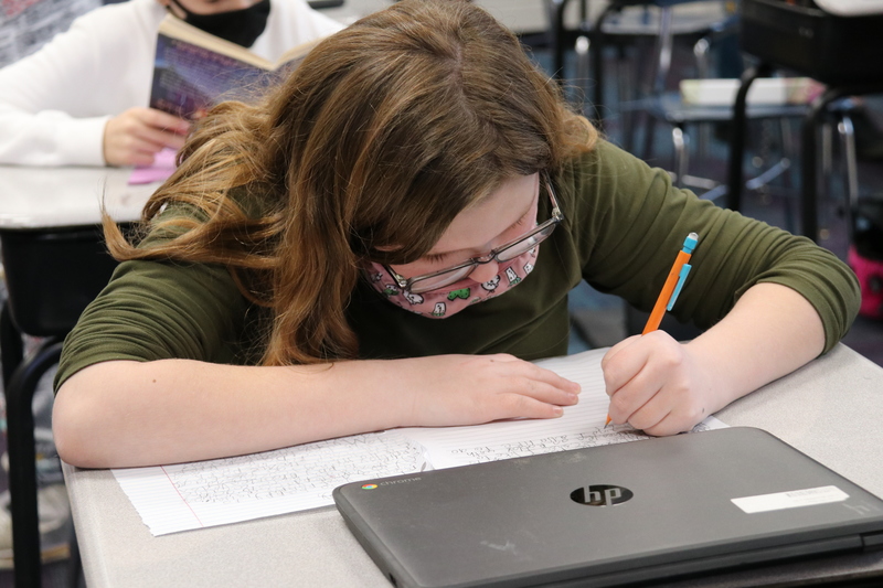 A student works on her pen pal letter