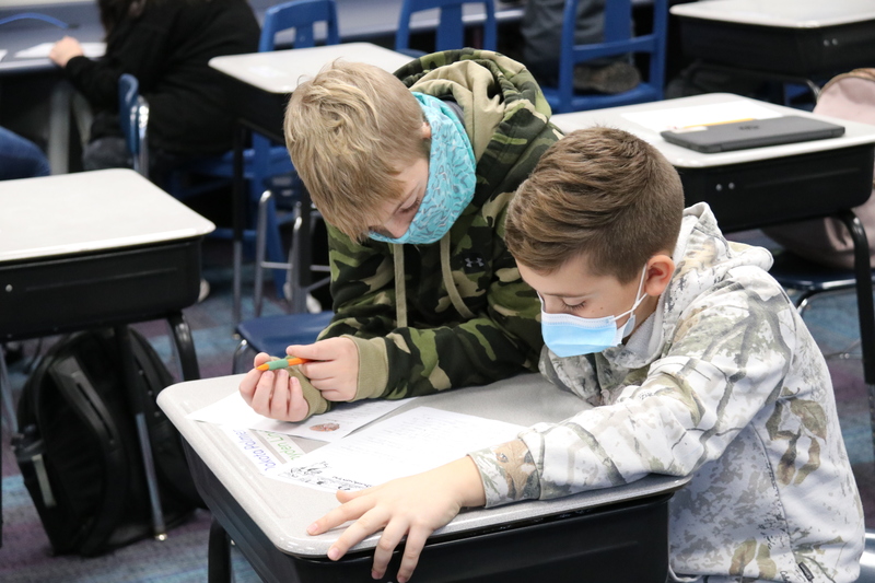 Two students work on peer reviewing each other's letter